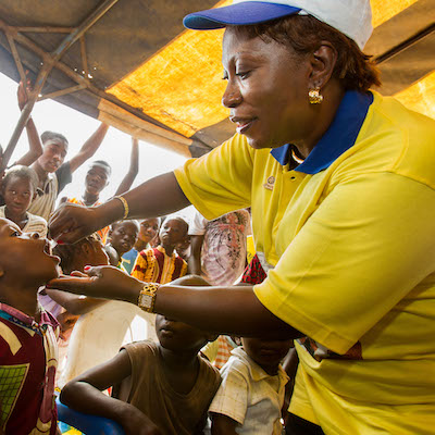 Rotarian Marie-Irene Richmond-Ahoua, Cote d'Ivoire PolioPlus Committee chair, inoculates a child with polio vaccine during a welcome ceremony kicking off a National Immunization Day in the village of Messikro, Cote d'Ivoire, 28 April 2013. Find the story in "The Rotarian," October 2013, pages 45-51.