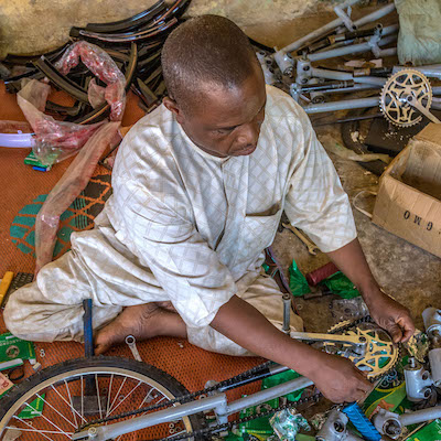 Isiaku Musa Maaji, a polio survivor, assembles a tricycle for other polio survivors at his workshop in Kaduna, Nigeria. He built his business by working with clients such as the local government and, more recently, with Rotary. He has become close to the Rotary family because he found them to be well organized, truthful and committed to helping the less privileged, particularly Rotary's support of polio immunization in Nigeria. He has begun participating in door-to-door polio vaccination efforts. 11 April 2019. Find the story in "The Rotarian," October 2019.